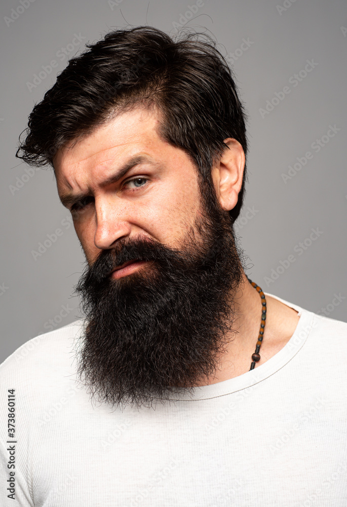 Fototapeta premium Portrait of confident serious man has beard and mustache, looks seriously, isolated. Hipster guy models in studio. Businessman thinking with expression looking. Handsome male model, closeup face.
