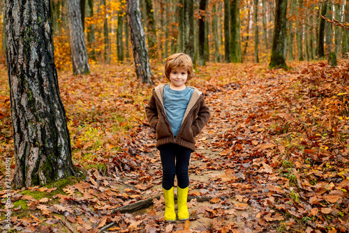 Smiling kid over autumn natural background, playing in the park.