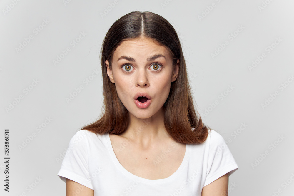 Surprised woman with open mouth in a white t-shirt on an isolated background close-up Surprised woman with open mouth in a white t-shirt on an isolated background close-up