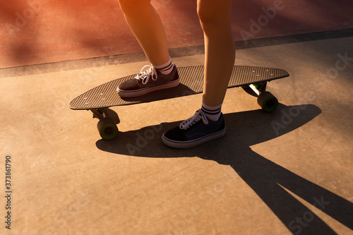 Crop teenager riding skateboard on street