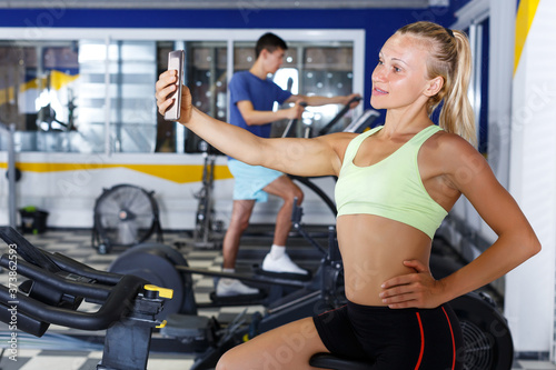 happy female athlete taking selfie during training in fitness center