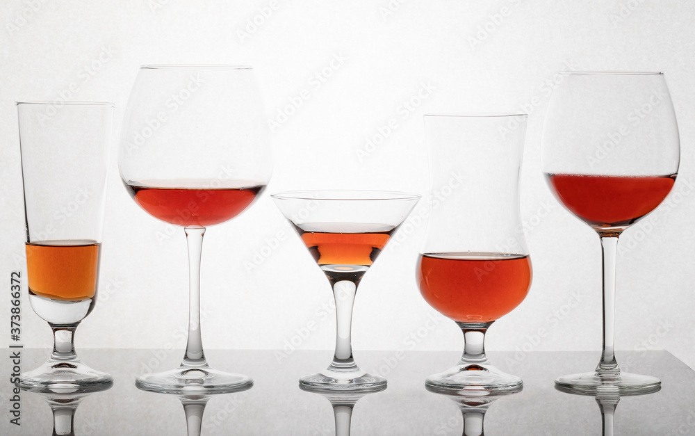 Glass glasses of different sizes with a drink on a white background. Glass glasses of different sizes with a drink on a white background.
