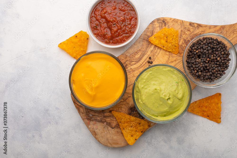 Chips and snacks with dips and salsa, and spices, top view on white background Chips and snacks with dips and salsa, and spices, top view on white background