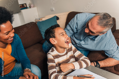Parents helping their son with his homework at home in living room.