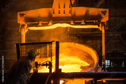 Steelworker at work near the tanks with hot metal photo