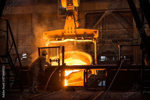 Steelworker at work near the tanks with hot metal photo