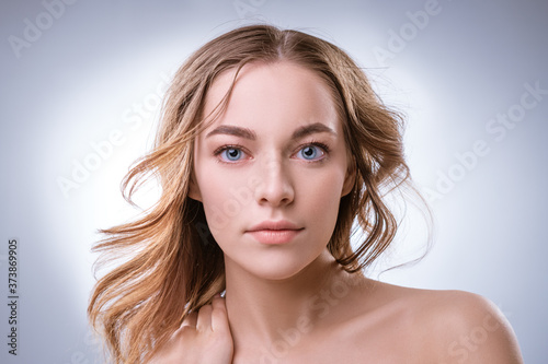 portrait of a young beautiful blonde girl of european appearance with blue eyes and long hair, posing on a white background