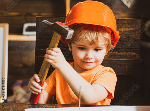 Fototapeta Little boy with a hammer makes repairs