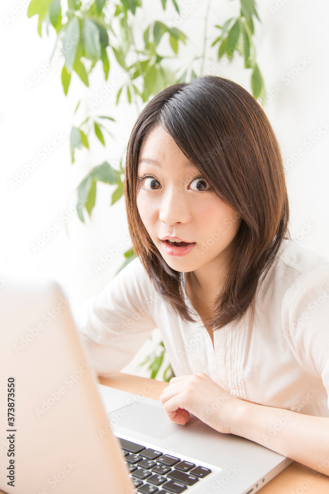 ノートパソコンを見て驚く女性
