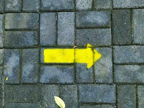 Yellow arrow sign on old stone brick wall direction pointer