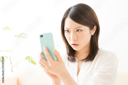 スマホを見て怒る女性