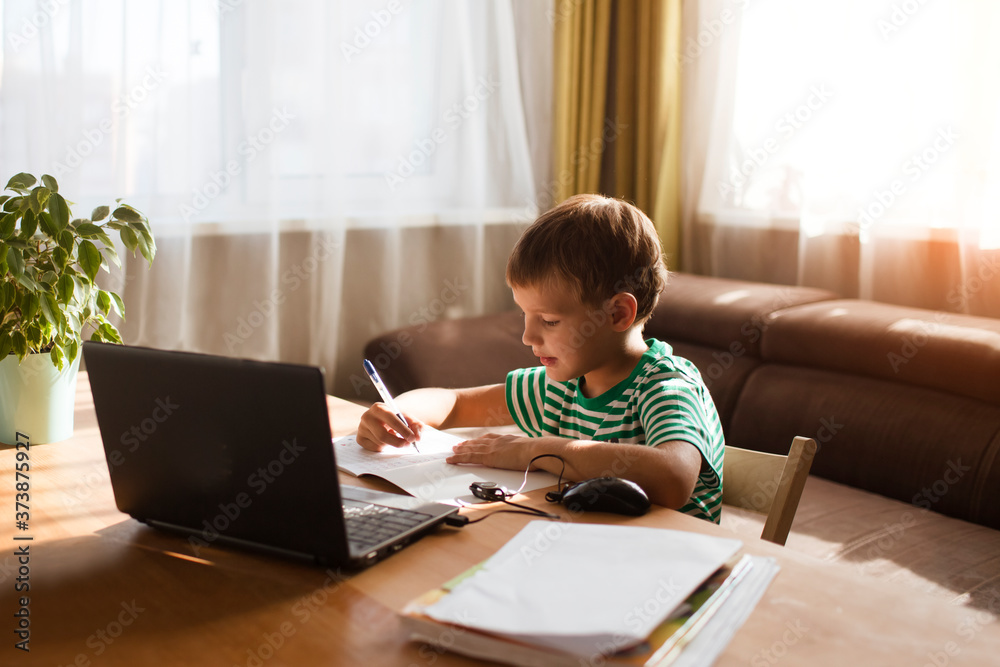 Preteen schoolboy doing his homework with laptop at home. homeschooling, distant learning