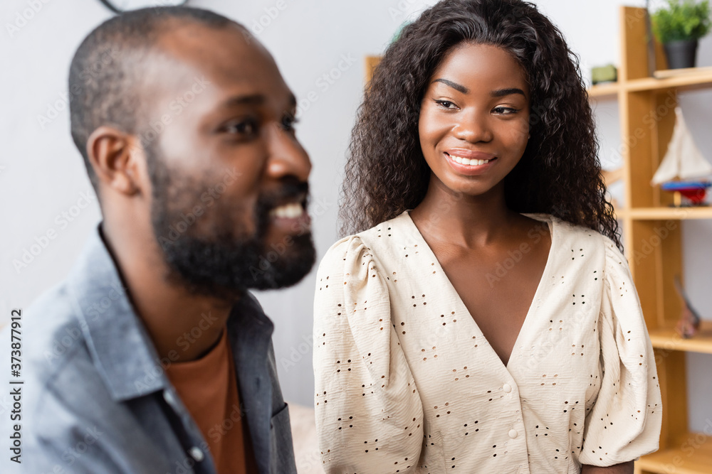 selective focus of african american woman in blouse looking at husband at home selective focus of african american woman in blouse looking at husband at home