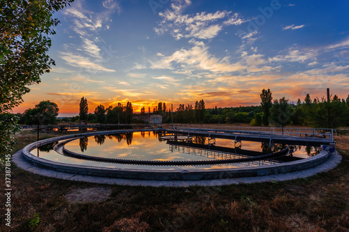Modern sewage treatment plant. Round wastewater purification tanks at sunset.