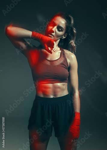 Portrait of beautiful female in boxing bandages standing in studio on gray background. Women's active lifestyle