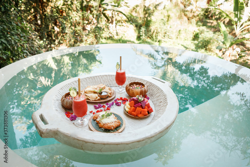 Floating breakfast for two  a large tray in the pool. Exotic summer diet. Tropical beach lifestyle
