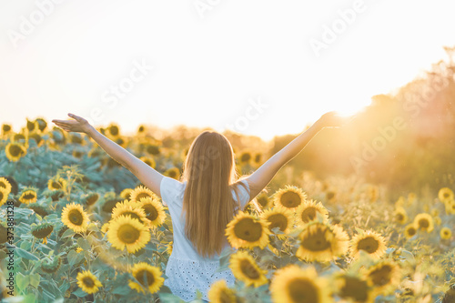 Young beautiful woman smiling and having fun in a sunflower field on a beautiful summer day.