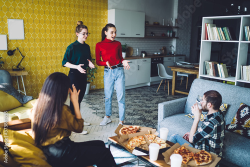 Enthusiastic friends talking and eating pizza together at home