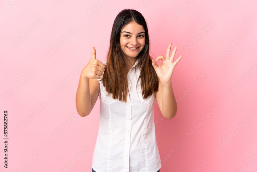 Young caucasian woman isolated on pink background showing ok sign and thumb up gesture Young caucasian woman isolated on pink background showing ok sign and thumb up gesture