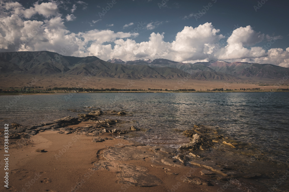 The coast of the high mountain lake Issyk Kul in Kyrgyzstan against the backdrop of the mountains in the day time