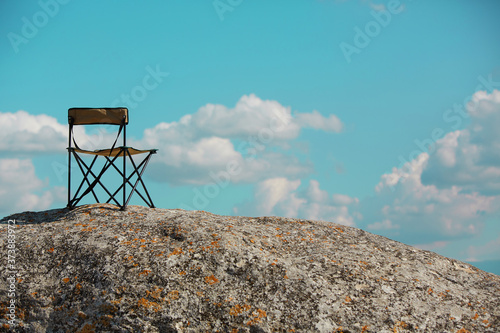 Time to travel. Adventure trip to mountains. Summer vacations. Tourism, travelling concept. Chair on top of high rock