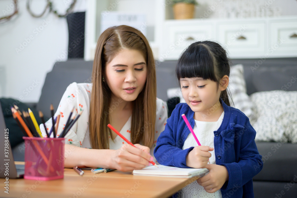 Asian Happy mom and daughter are using laptop for studying online via internet at home. E-learning Concept during quarantine time. Asian Happy mom and daughter are using laptop for studying online via internet at home. E-learning Concept during quarantine time.