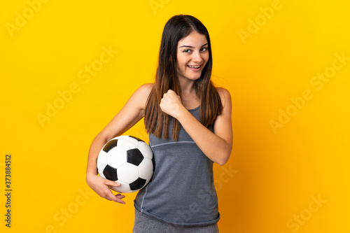 Young football player woman isolated on yellow background celebrating a victory © luismolinero
