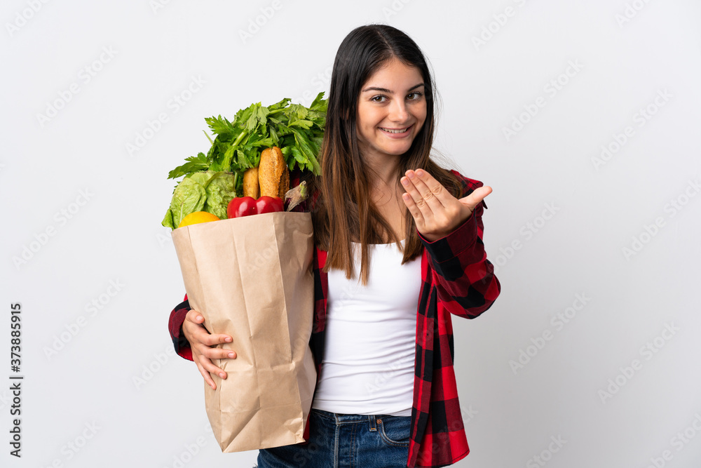Young caucasian with vegetables isolated on white background inviting to come with hand. Happy that you came Young caucasian with vegetables isolated on white background inviting to come with hand. Happy that you came