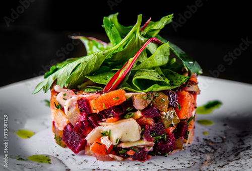 traditional vegetables vinegret salad in white plate on black wooden table background photo