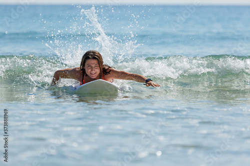 girl on a surfboard swims on the sea, summer, sunny day, clear water