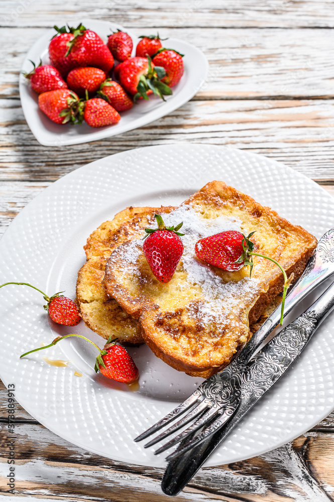 Two fried French toast with powdered sugar and strawberries. White background. Top view