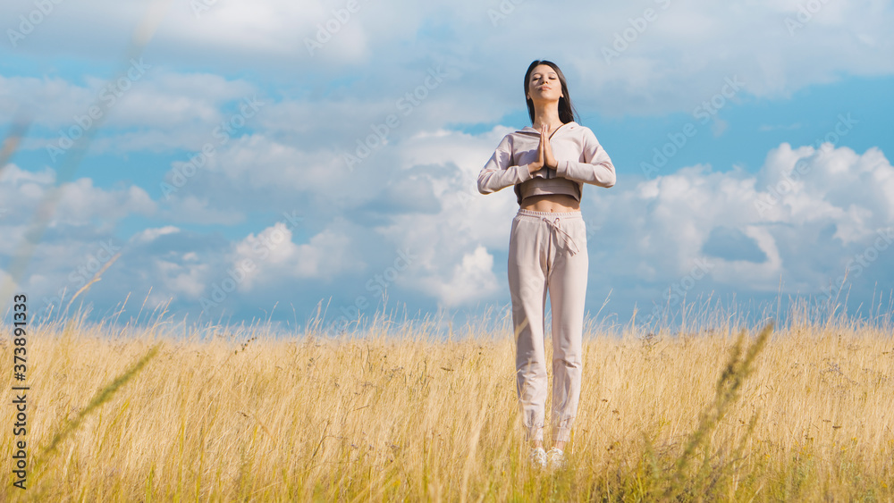 Fototapeta premium Young nice woman doing yoga in yellow field. Care concept