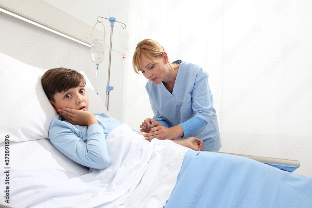 Nurse medicating sick and afraid child lying in bed in hospital room and getting him the drip Nurse medicating sick and afraid child lying in bed in hospital room and getting him the drip
