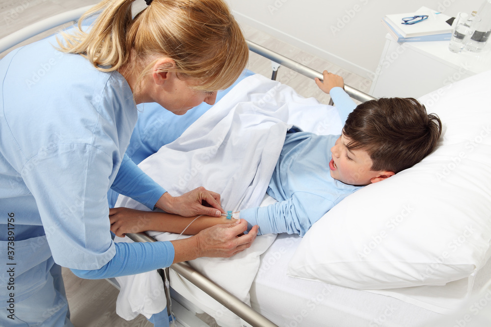 Fototapeta premium Up view of nurse medicating sick child lying in bed in hospital room and getting him the drip