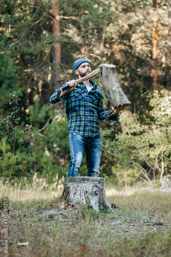 Stylish bearded forester chopping wood with an axe