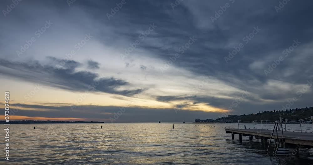 Time lapse of dramatic and colorful sunset over concrete pier and small town Portoroz in Slovenia. Adriatic Sea in summer. People taking photos. Wide shot, zoom out, 4K Time lapse of dramatic and colorful sunset over concrete pier and small town Portoroz in Slovenia. Adriatic Sea in summer. People taking photos. Wide shot, zoom out, 4K
