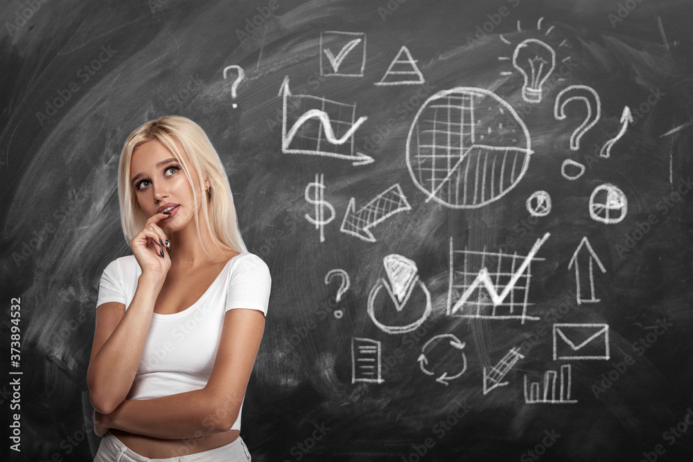 Thinking young european blonde woman and optimisation marketing and business process icons drawn on blackboard Thinking young european blonde woman and optimisation marketing and business process icons drawn on blackboard
