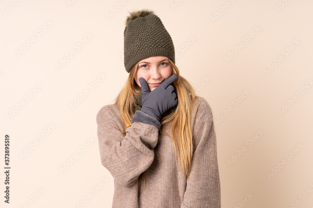 Teenager Ukrainian girl with winter hat isolated on beige background thinking an idea Teenager Ukrainian girl with winter hat isolated on beige background thinking an idea