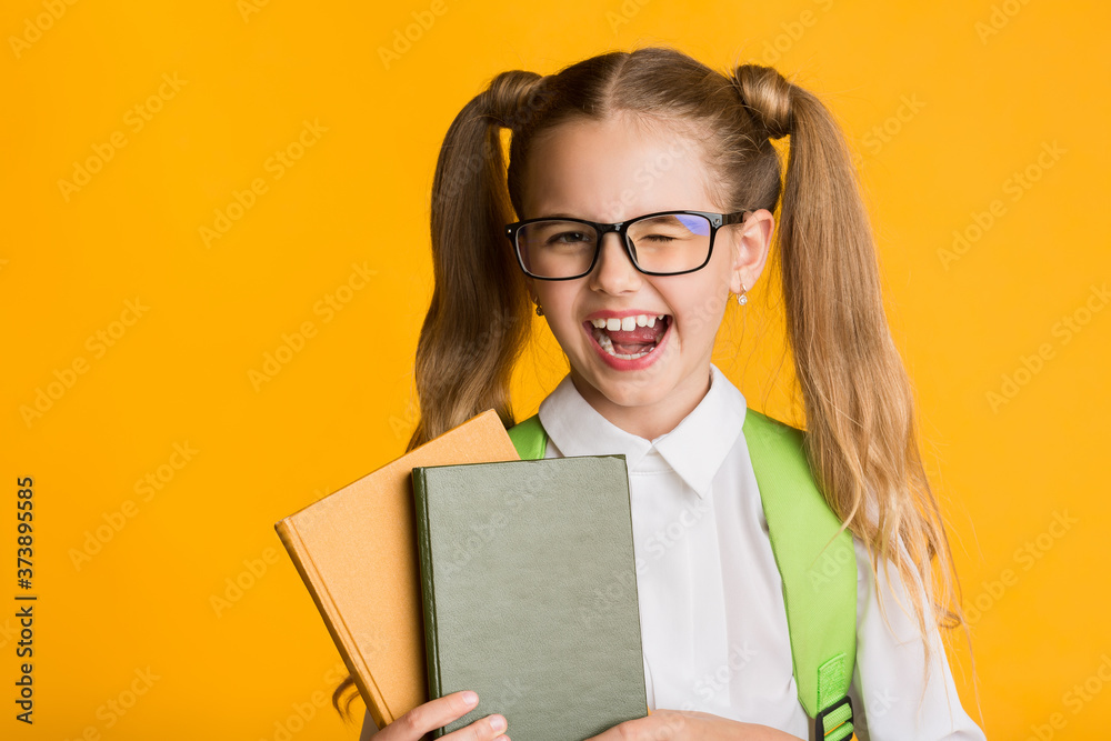 Funny School Girl Winking At Camera Holding Books In Studio Funny School Girl Winking At Camera Holding Books In Studio