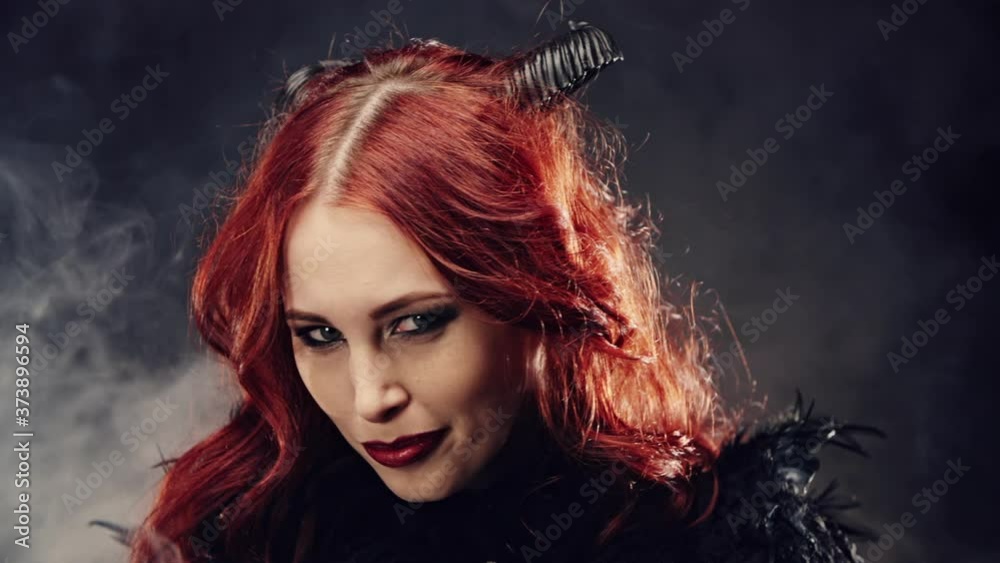 Portrait witch girl with red hair and devil horns. Woman smiling devilishly and laughing. Concept of cult of dark forces, rituals for summoning demon, halloween, occultism, esoterics. Portrait witch girl with red hair and devil horns. Woman smiling devilishly and laughing. Concept of cult of dark forces, rituals for summoning demon, halloween, occultism, esoterics.