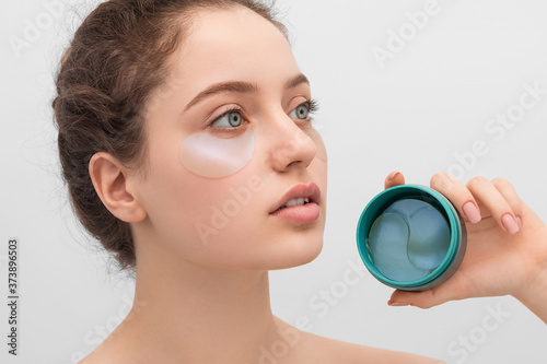 A young woman holds a box of eye patches in her hand.