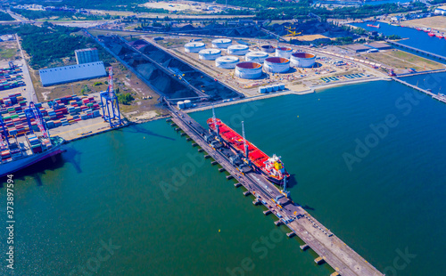Loading coal anthracite mining in port on cargo tanker ship with crane bucket of train. Aerial top view. © netsay