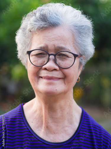 Portrait of an elderly woman wearing eyeglasses looking at camera while standing in a garden