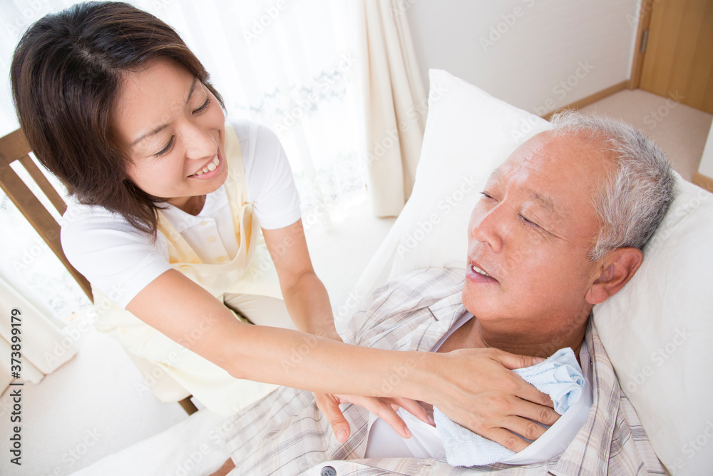Fototapeta premium シニア男性の体を拭く介護士