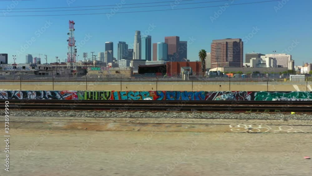 Flying right with a drone infront of abandoned train tracks with the Los Angeles Skyline in the Background, California USA