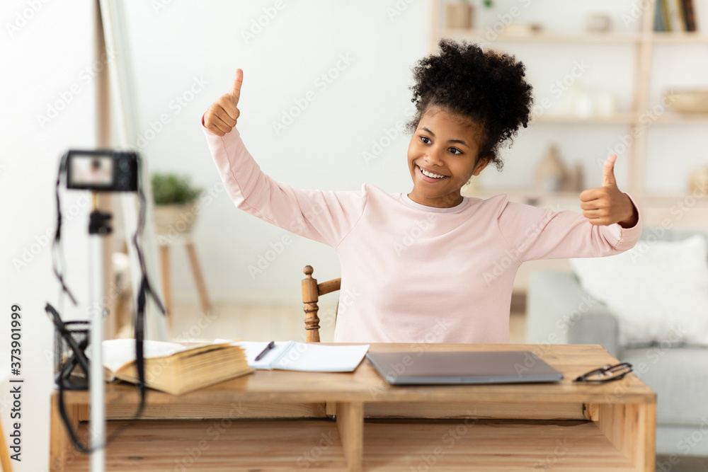 Teen Blogger Girl Making Video Gesturing Thumbs-Up Sitting At Home Teen Blogger Girl Making Video Gesturing Thumbs-Up Sitting At Home