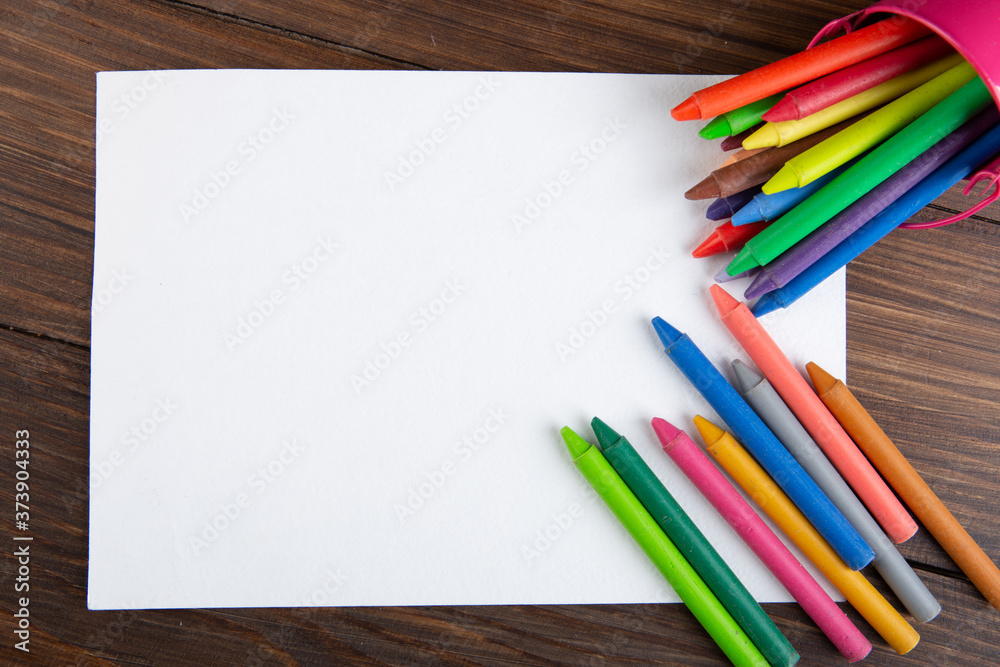 Obraz premium colored crayons and blank page on the wooden table