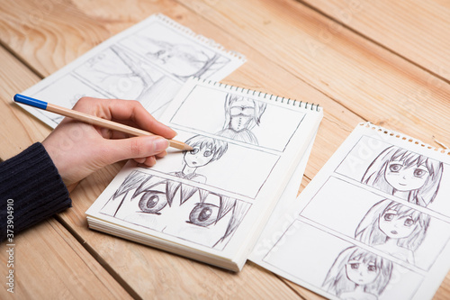 Artist drawing an anime comic book in a studio.