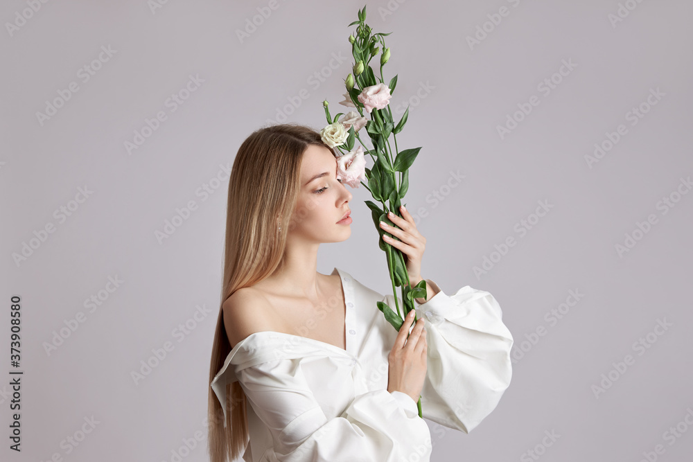 Beauty portrait woman with pink eustoma flowers in her hands. Natural cosmetics for face and body skin care. Beautiful girl in a white shirt Beauty portrait woman with pink eustoma flowers in her hands. Natural cosmetics for face and body skin care. Beautiful girl in a white shirt