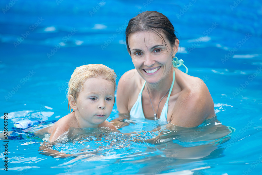 Cute toddler boy, swimming in pool with board